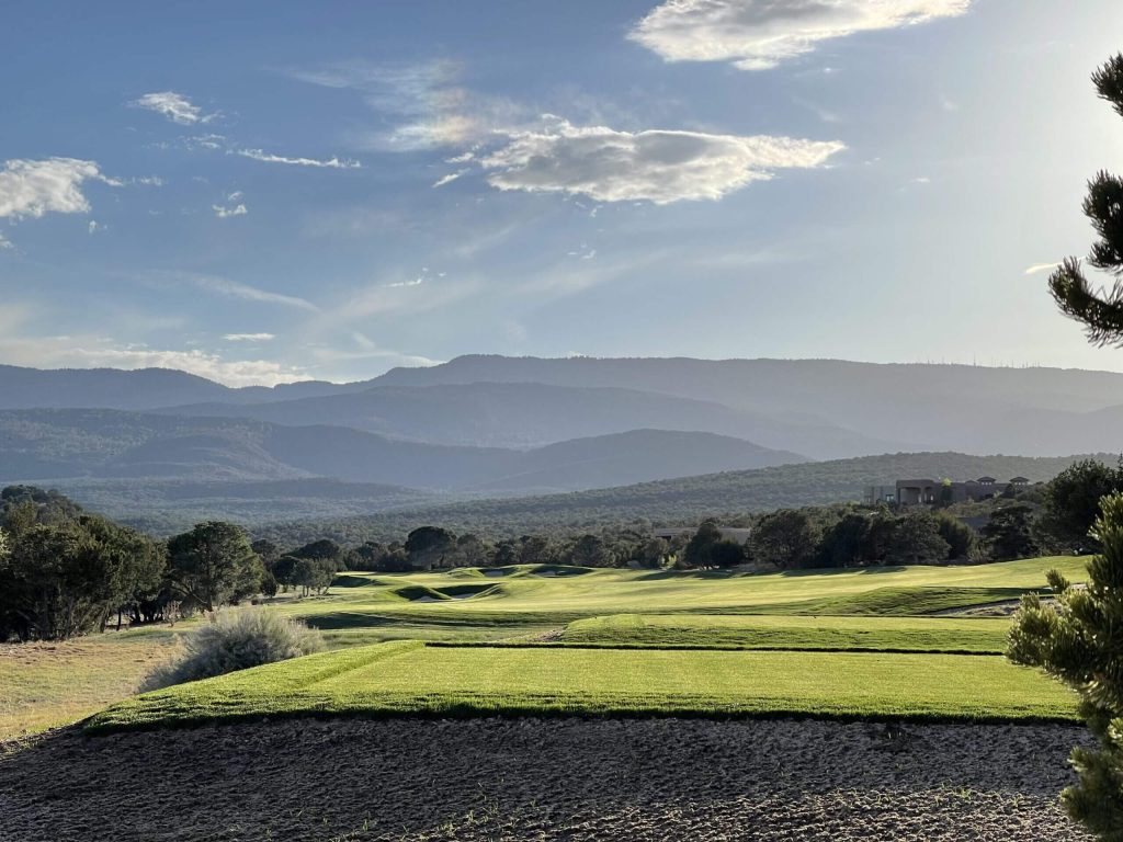 Scenic mountain-view golf course fairway at sunset with rolling hills and trees