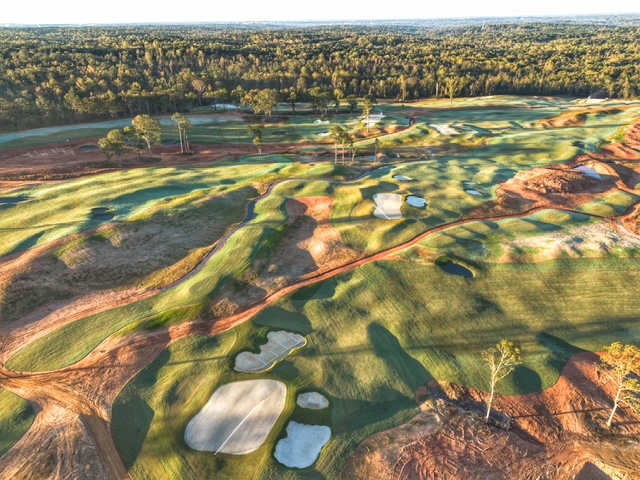 Aerial view of a championship golf course with rolling fairways, bunkers and greens at sunrise